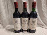 trois bouteilles de vin rouge sont alignées sur une nappe blanche