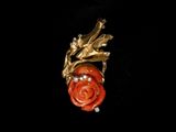une image représentant une broche en forme de rose rouge sur fond noir