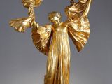 une statue en or représentant une femme tenant une fleur dans ses mains
