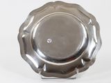 a silver plate on a stand on a white surface