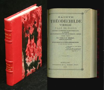 an old book sitting on top of a black table next to a red book