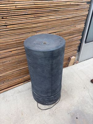 a black trash can sitting on the sidewalk next to a wooden wall