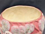 a pink bowl with flowers on it sitting on a table