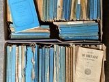 une boîte remplie de livres posée par terre, à côté d'une pile de livres