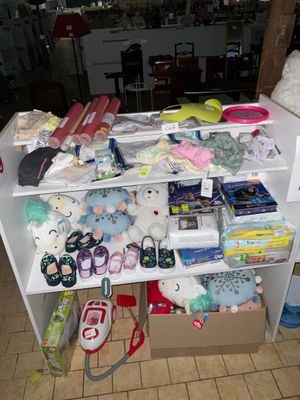 une étagère blanche remplie de toutes sortes d'objets, posée sur un sol carrelé