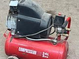 a red compressor sitting on the ground next to a black and white dog