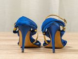 blue high heeled sandals with gold accents on a wooden surface