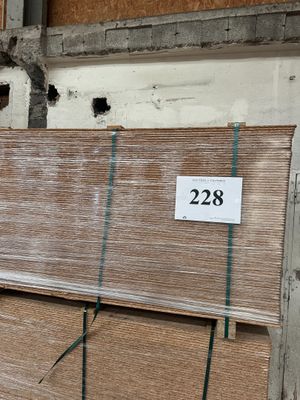 une grande pile de panneaux de contreplaqué dans un entrepôt, sur laquelle est apposée une étiquette de prix
