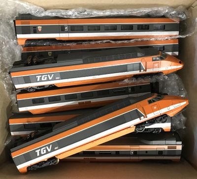 Plusieurs trains orange et noirs se trouvent dans une boîte posée sur une table
