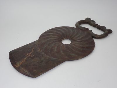 une vieille clé en forme de coquillage posée sur une surface blanche