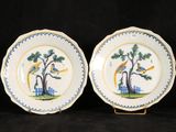 two blue and white plates with birds on them sitting on a black surface
