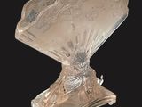 une assiette en argent ancien représentant un éventail posé sur un socle, sur fond noir