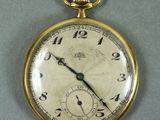 un gros plan d'une montre de poche en or posée sur une surface grise