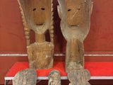 deux sculptures en bois représentant un homme et une femme assis sur un banc