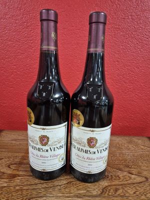 two bottles of wine sit on a table in front of a red wall