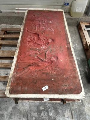 une grande table rouge sur laquelle est sculpté un homme