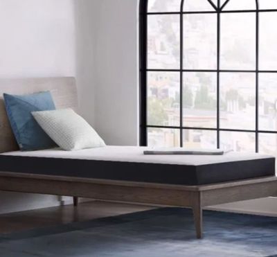 un lit avec un matelas, placé devant une fenêtre
