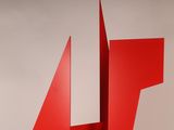 sculpture made of red metal with a triangular shape on top of it