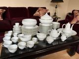 une table sur laquelle sont disposés de nombreux plats et tasses blancs