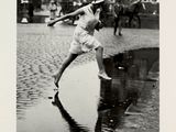 photographie en noir et blanc d'une femme brandissant une batte de baseball dans une rue mouillée