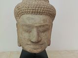 sculpture of a head of a buddha on a black stand