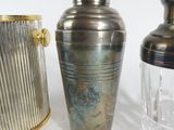 three glass vases and a metal shaker on a table