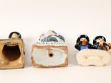 three small figurines sitting next to each other on a white surface