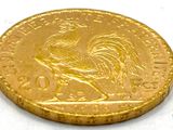 gold coin with a rooster on it on a white surface