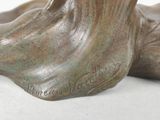 a bronze statue of a dog laying down on a white surface