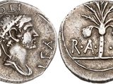 a silver coin with an image of a woman and a tree on it