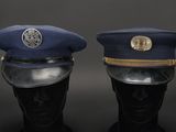 pair of military hats on mannequin heads against a black background