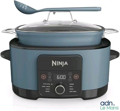 a blue and black crock pot with a spoon in it
