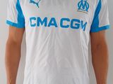 Cet homme porte une chemise blanche et bleue et un pantalon noir.