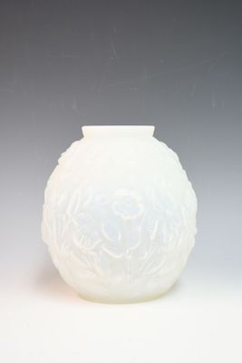 un vase blanc posé sur une table, sur fond gris