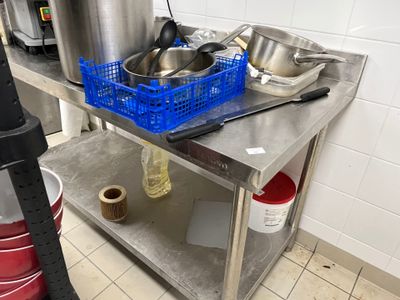 une table en métal sur laquelle sont posés des casseroles et des poêles, dans une cuisine
