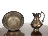 un pichet en argent et une assiette en argent posés sur une table