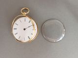 une montre de poche en or et un verre transparent posés sur la table