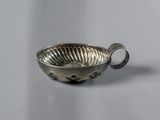 a small silver bowl with a handle on a table