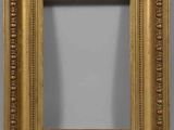 un miroir à cadre doré orné d'un motif décoratif, accroché au mur