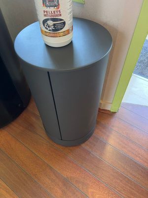 a black trash can sitting on top of a wooden table