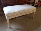 a white bench with a white cushion on top of it