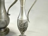 two silver vases sitting next to each other on a table