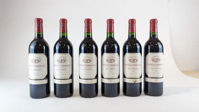six bouteilles de vin sont alignées sur une table