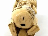 a figurine of a teddy bear laying down on a white surface
