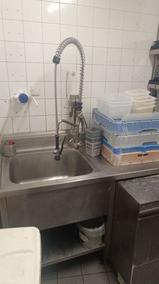 un évier en inox dans une cuisine où il y a beaucoup de vaisselle