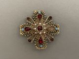 a close up of a gold broochle with red and white stones