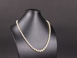 un collier de perles blanches sur un mannequin, sur fond noir