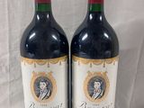 two bottles of red wine sitting next to each other on a table