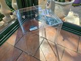 une table claire avec un plateau en verre, posée sur un sol carrelé