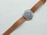 a close up of a watch on a white surface with a brown strap